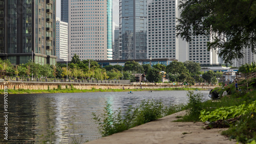 view of a public park with a lake in Jakarta in the morning with a background of modern buildings on the lake side