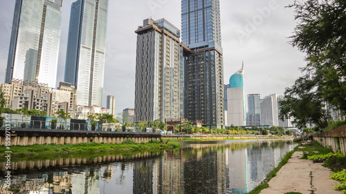 view of a public park with a lake in Jakarta in the morning with a background of modern buildings on the lake side