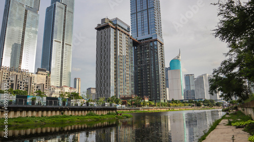view of a public park with a lake in Jakarta in the morning with a background of modern buildings on the lake side