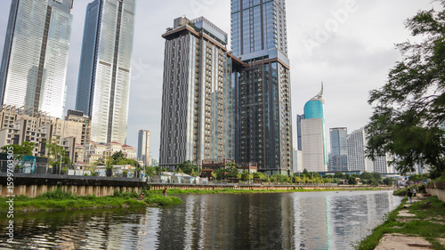 view of a public park with a lake in Jakarta in the morning with a background of modern buildings on the lake side