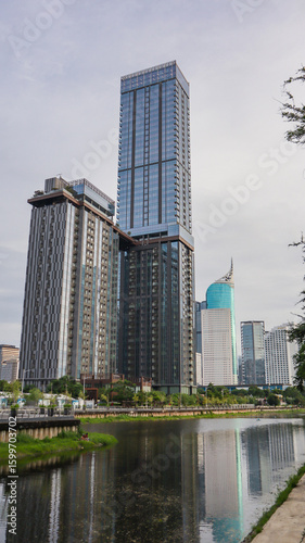 view of a public park with a lake in Jakarta in the morning with a background of modern buildings on the lake side