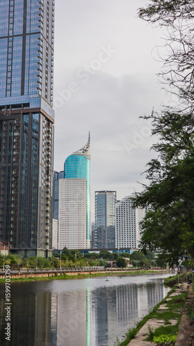 view of a public park with a lake in Jakarta in the morning with a background of modern buildings on the lake side