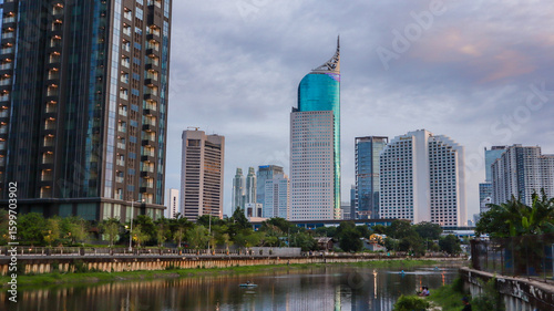 view of a public park with a lake in Jakarta in the morning with a background of modern buildings on the lake side