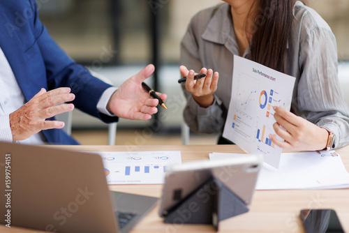 Group of confident business people point to graphs and charts to analyze market data, balance sheet, account, net profit to plan new sales strategies to increase production capacity.	