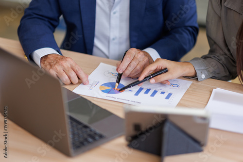Group of confident business people point to graphs and charts to analyze market data, balance sheet, account, net profit to plan new sales strategies to increase production capacity.	
