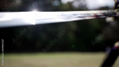 Gleaming steel blade of a sword held ready for historical combat in a natural outdoor setting.