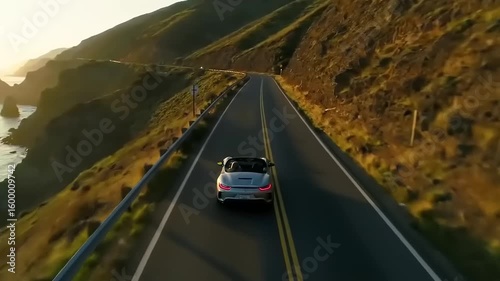 Scenic coastal drive along a winding road with a convertible car at sunset, ocean waves crashing nearby