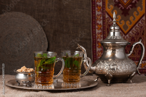 still life with traditional Arabic mint tea in drinking glasses and silver traditional silver pot