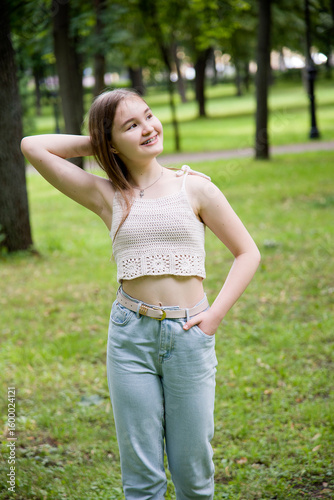 young brunette smiling woman in hand made top posing in sunny park near tree on summer 