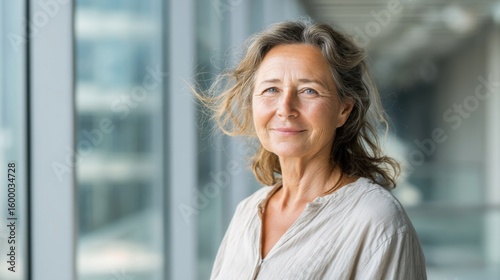 Free Download Experienced mature woman with gray hair standing in modern office building background. - GFXLoad