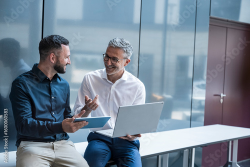 Business manager and colleague discussing project in modern office