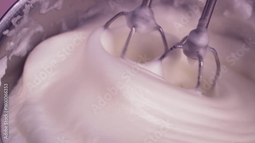 Close-up slow motion of egg whites being whisked until they nearly form meringue. 