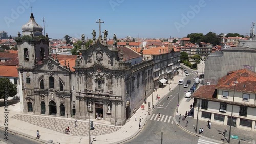 Aerial drone view of historic baroque church with detailed facade in Viana do Castelo, Portugal. City streets, tiled roofs, and coastal skyline appear under clear blue sky in bright daylight.