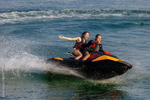 Fotografi Happy couple riding a jet ski on water