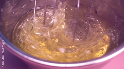 Slow motion close-up of egg whites being whisked until they start to foam. 