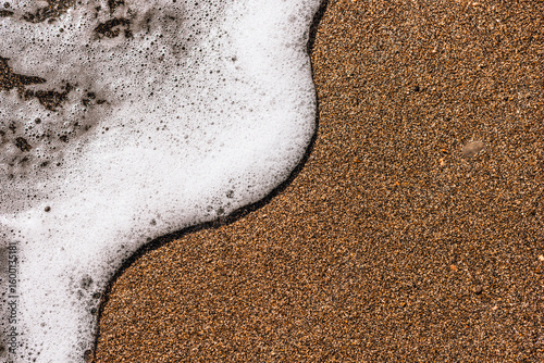 Photography Close-up of sandy beach with gentle waves lapping at the shore