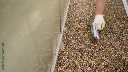 Construction worker spreading gravel with trowel on roof