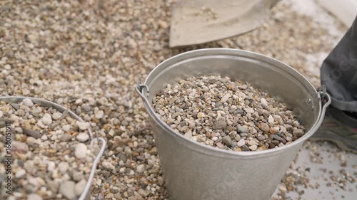 Construction worker pouring gravel into metal bucket