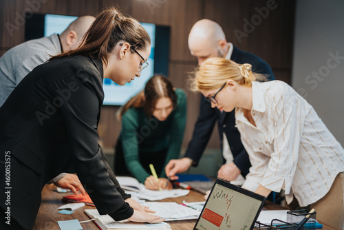 Tapet Colleagues working together in a corporate office setting, reviewing documents and charts, engaging in decision making and team building in a professional environment