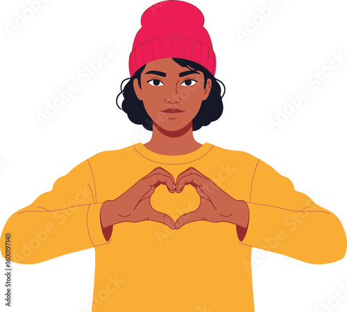 Young woman with dark skin and a pink beanie making a heart shape with her hands, wearing a yellow sweater.