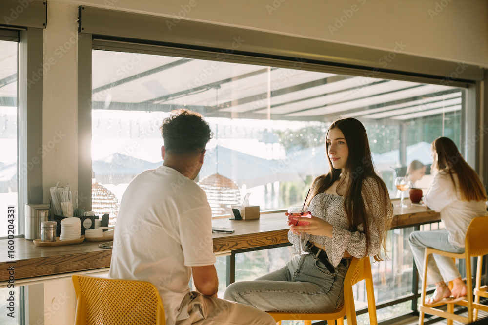 Obraz premium Young couple talking and drinking cocktails in a cafe