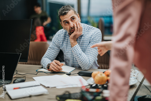 Foto Businessman seated while attentively listening during an office interaction, reflecting on a subject with apparent concern and focus