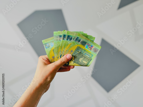 Hand holding stack of currency banknotes against abstract background  