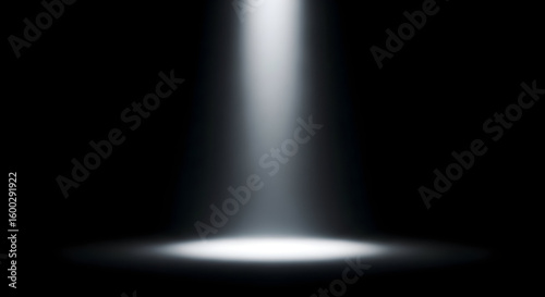 A beam of white light shining down from above onto a dark surface in a studio setting backdrop shot