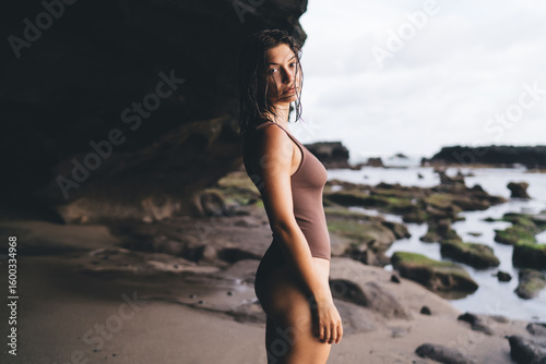 Canvas Print Young woman stands near rocks, gazing calmly into distance, expressing quiet defiance, natural confidence and grounded independence disconnected from digital pressure and noise
