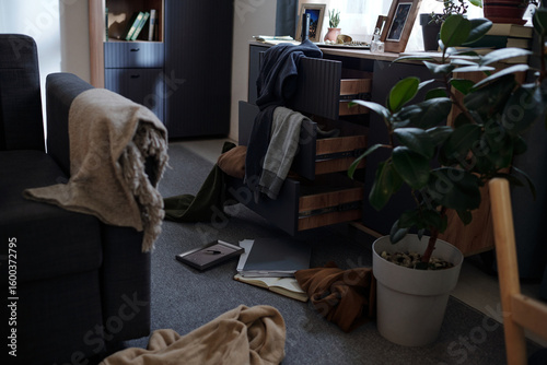 Foto Messy living room scene showing open drawers with scattered clothing and papers
