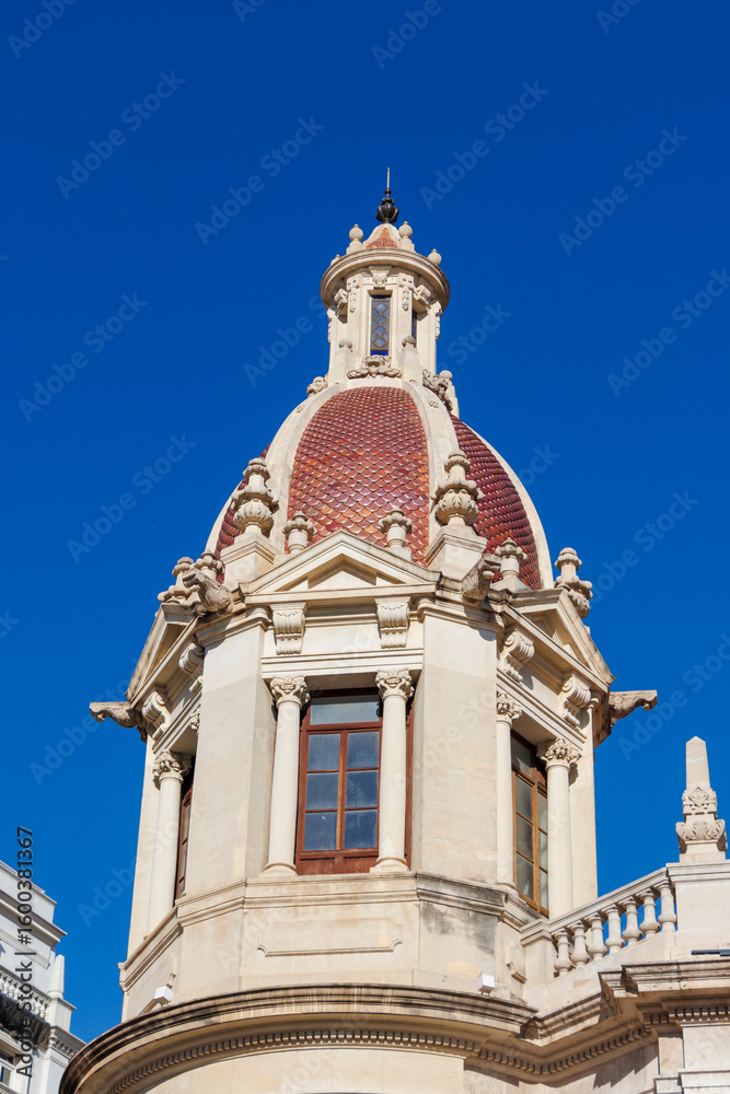 Fototapeta premium A close-up view of a historic building's ornate dome in Plaza del Ayuntamiento, showcasing intricate architectural designs under a clear blue sky. Perfect for travel and architecture themes.
