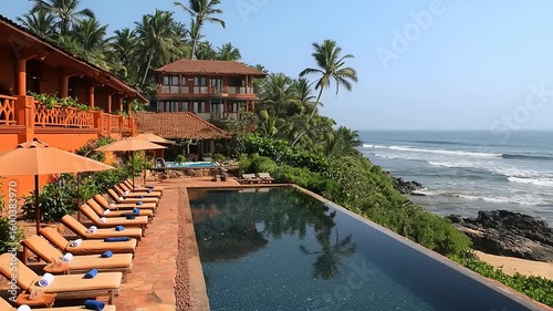 Infinity pool overlooking the ocean with tropical vegetation and buildings.