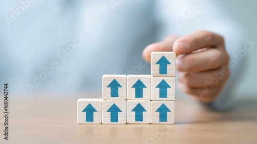 A person is holding a stack of wooden blocks with blue arrows on them