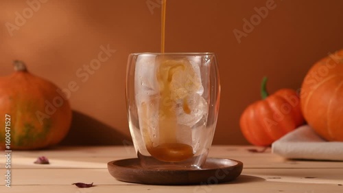 Iced pumpkin latte prepared step by step, cozy autumn atmosphere with pumpkins and warm brown tones, refreshing seasonal coffee drink.