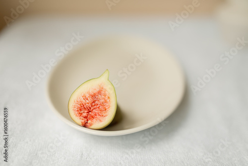 Fresh fig fruit cut in half on plain white plate