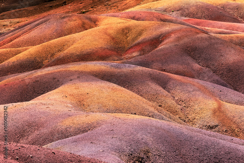 View of earth's crust with undulating hills displaying a spectrum of colors, from ochre and rust to lavender and gold, Chamarel, Mauritius.