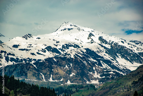 Snow-covered mountain peak with forested slopes.
