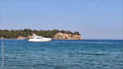 A white pleasure yacht in the blue Mediterranean sea against the backdrop of a picturesque forest place