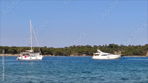 A white pleasure yacht in the blue Mediterranean sea against the backdrop of a picturesque forest place
