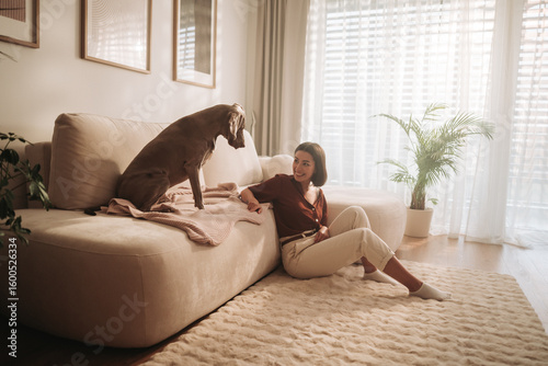 Cozy Indoor Moment A Woman Enjoys Quality Time with Her Dog While Sitting on a Sofa