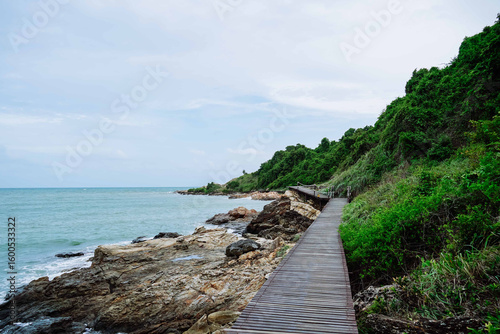 The wooden walkway beside the rock beach at Khao Laem Ya Mu Ko Samet National Park. Wooden bridge along sea shore. Wooden bridge along rocky coastline hills. Travel and tourism.