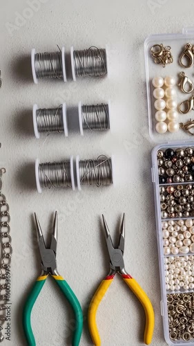 Jewelry making tools and supplies on a table. Creative craft activity with pliers, wire, and beads. Hobby or DIY project footage