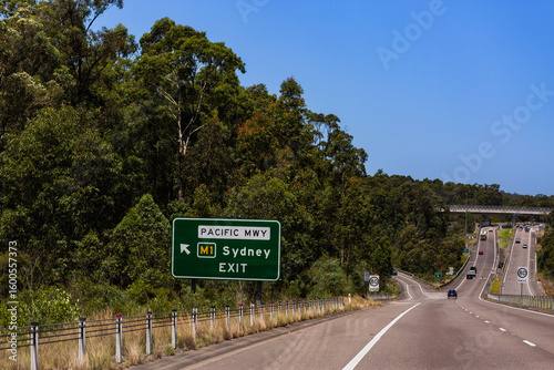 roadside sign with arrow saying pacific highway M1 Sydney exit on sunlit day in Australia