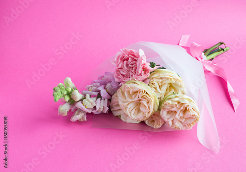Beautiful small bouquet with pink and white roses on a pink background.Close-up.