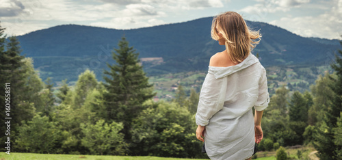 Young woman in white shirt on the background of mountains and blue sky