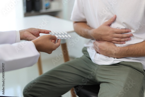 Man with abdominal pain, bloating, diarrhea goes to the doctor at medical clinic. Female doctor is diagnosing a patient abdominal pain in the examination room at the hospital.