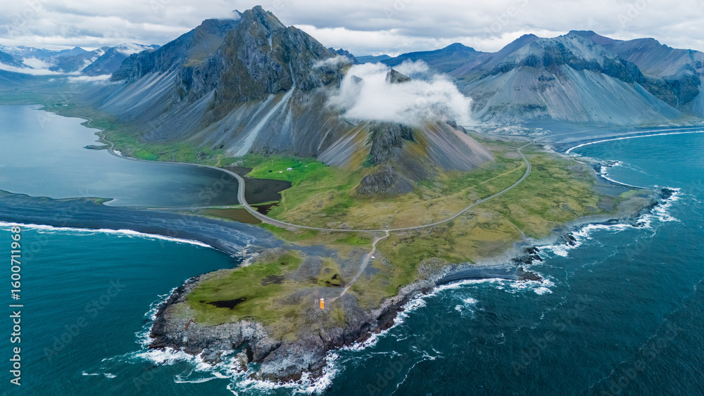 Fototapeta premium A majestic aerial view captures Hvelnes nature reserve mountain rising dramatically above the coastal landscape of Iceland.