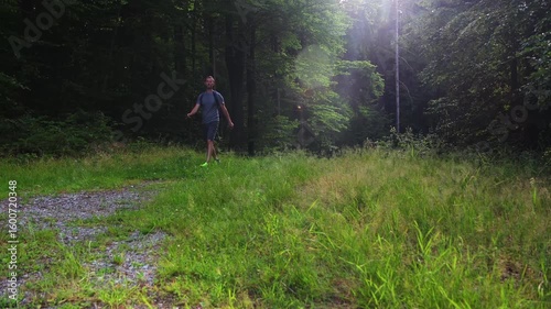 Man with backpack walking on forest path. Leisure, relaxation concept, side camera movement