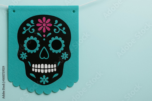 colorful day of the dead papel picado decoration with intricate sugar skull design on teal background celebrating mexican tradition