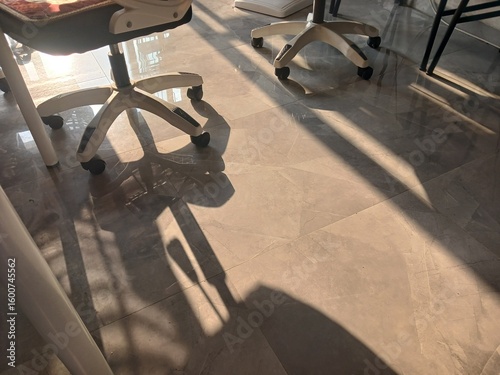 Office chair and desk chair casting long shadows on the sunlit floor